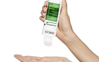 shampoo anti caspa dercos en la mano