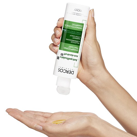 persona aplicandose en las manos shampoo anti caspa